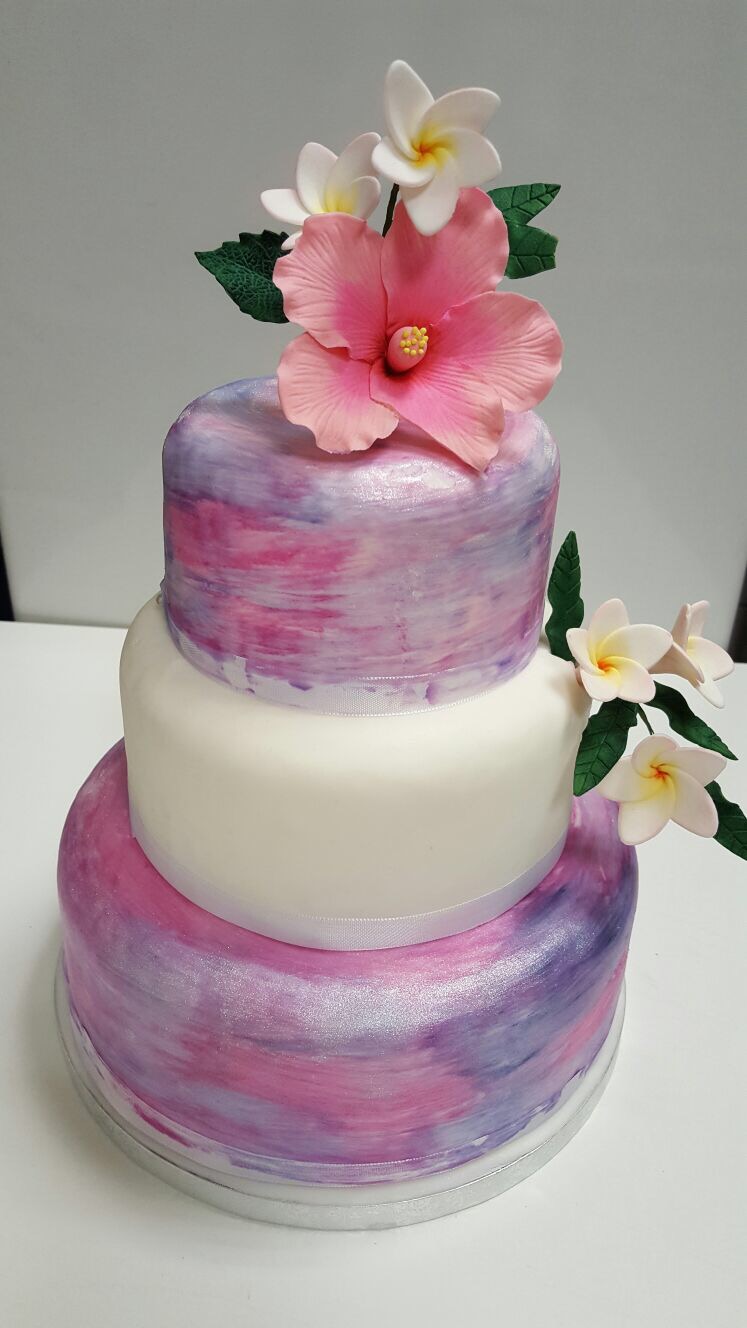 Dreistöckige Torte in Pink und Violett mit Hibiskus- und Frangipani-Blüten aus Zucker